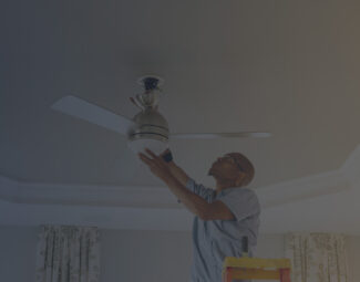 Black Man Climbed on a Ladder Installing a Ceiling Fan