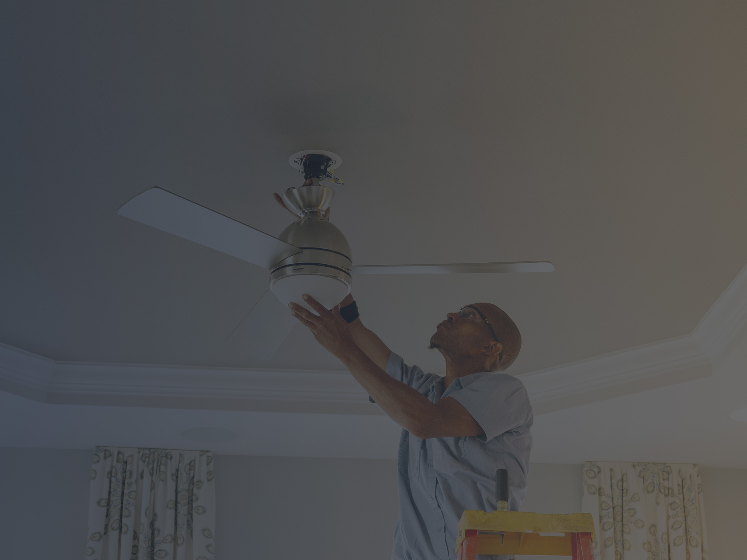 Man Climbed on a Ladder Installing a Ceiling Fan