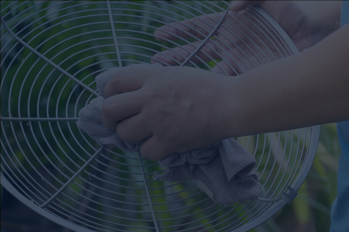 Man Cleaning the Grille of a Misting Fan Outdoors