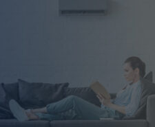 Woman Reading a Book on a Sofa with Wall Air Conditioner On