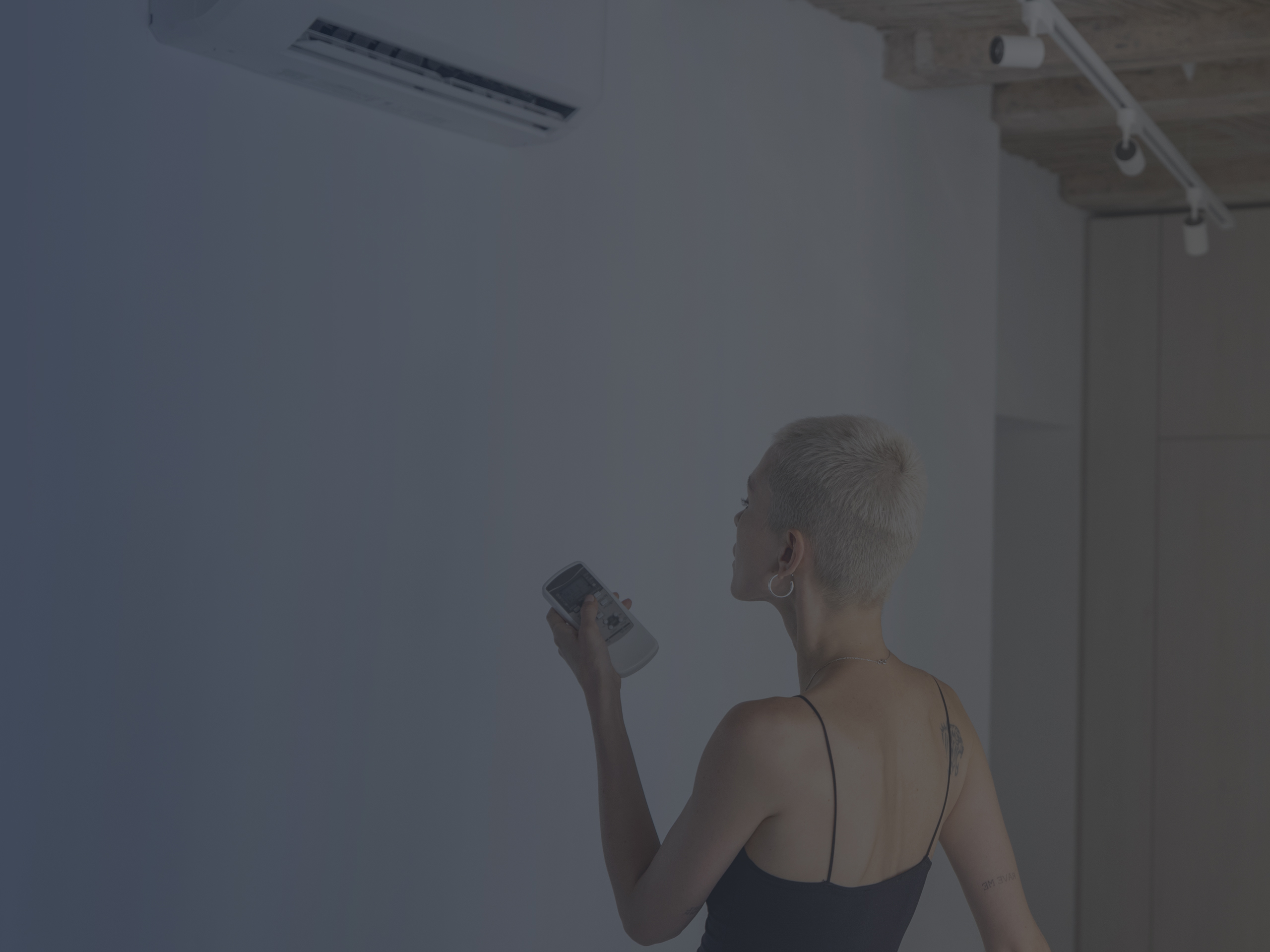 Woman Sets the Temperature on the Air Conditioner with Remote Control