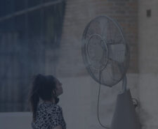 Woman Standing in Front of Misting Fan Outside