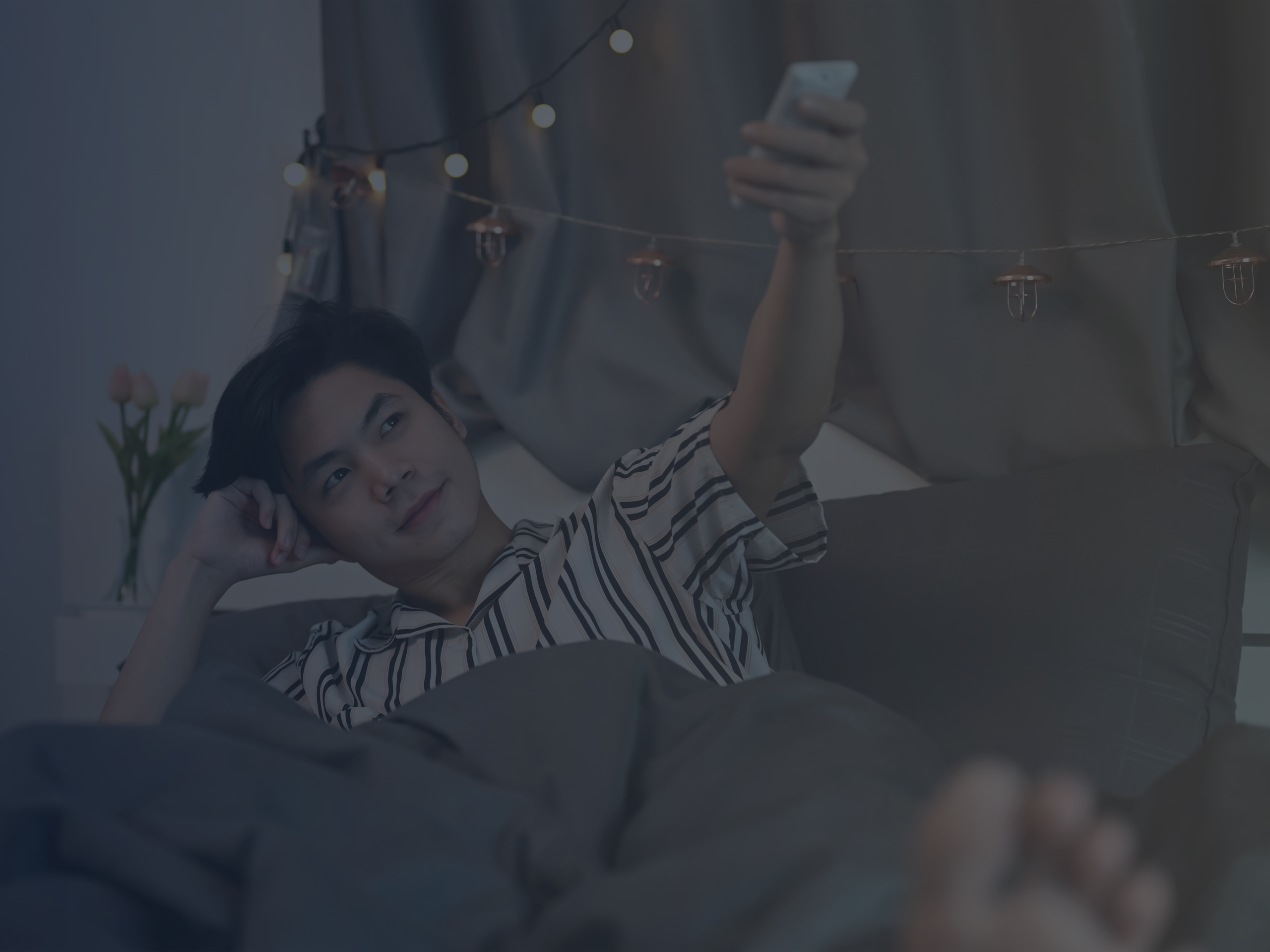 Young Man in Bed Operating the Air Conditioner