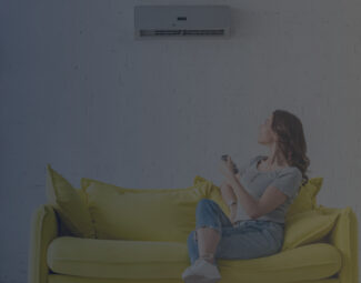 Young Woman Sitting on Yellow Sofa under Air Conditioner at Home