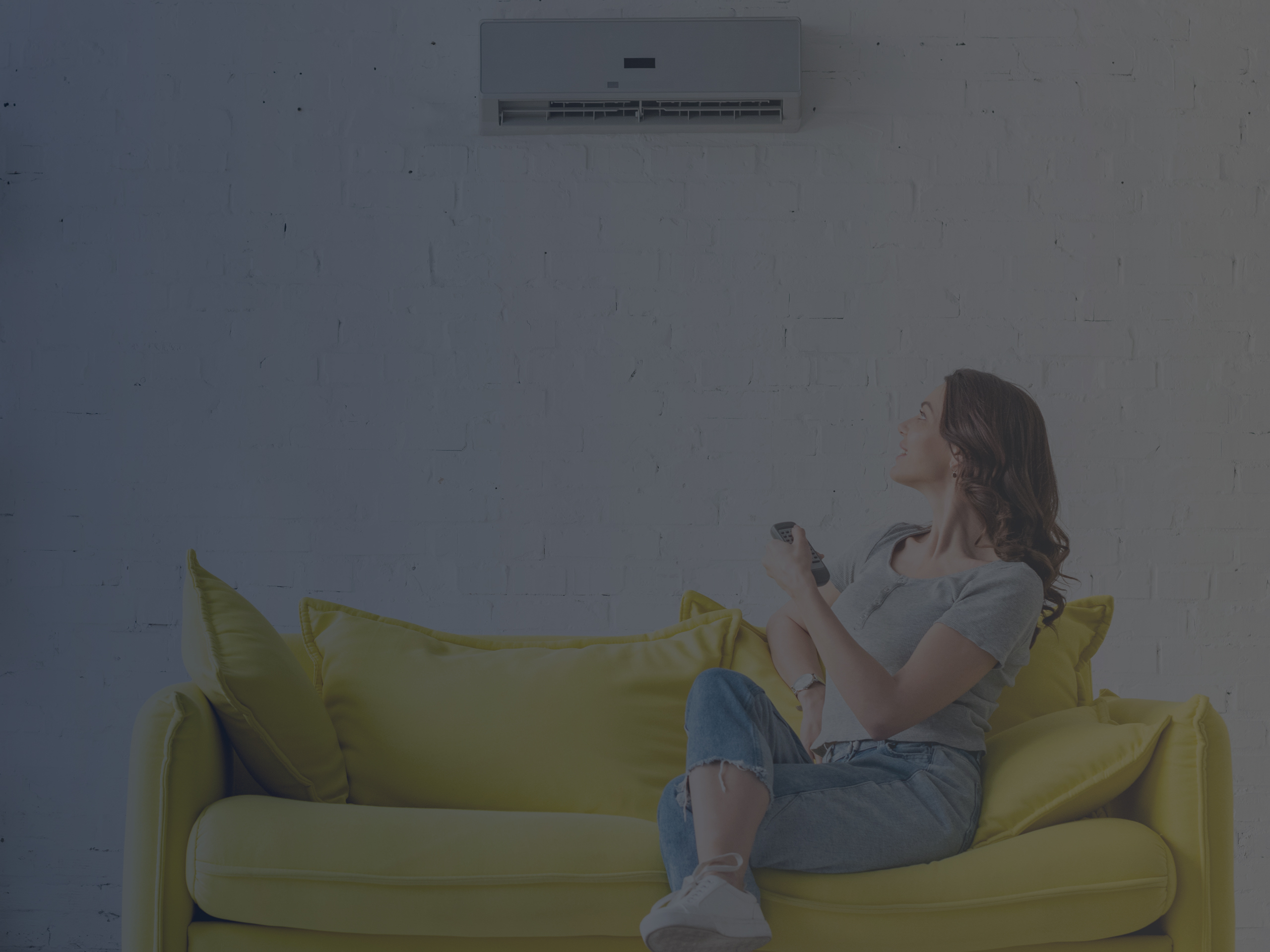 Young Woman Sitting on Yellow Sofa under Air Conditioner at Home