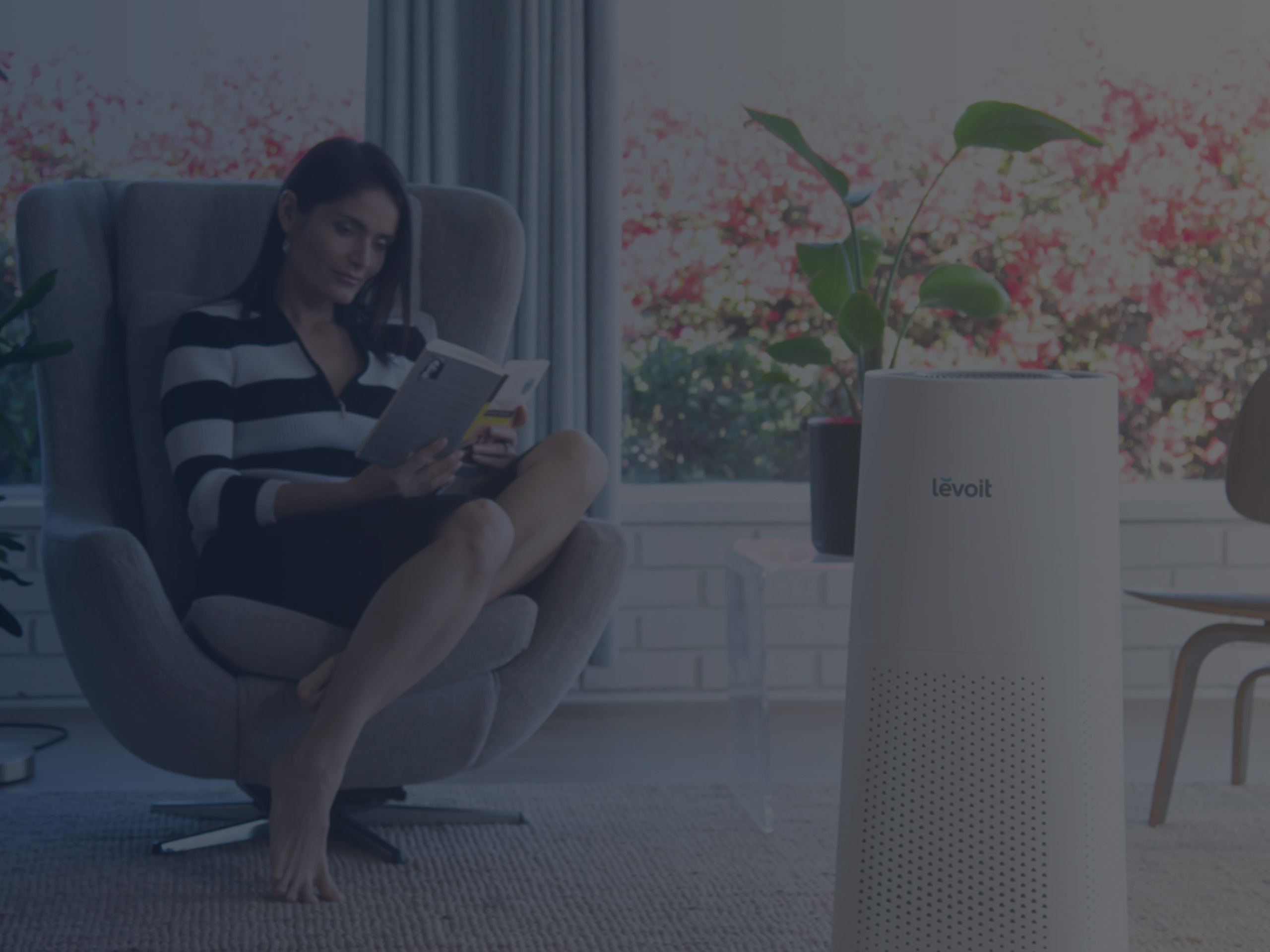 Woman Reads a Book while Air Ionizer Cleans Indoor Air