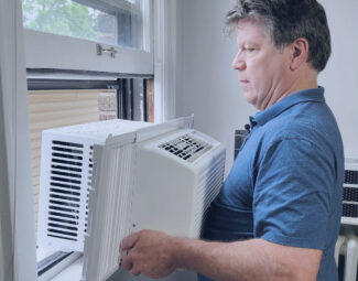 Man Tanking Out Window AC Unit to Inspect Operating Issues